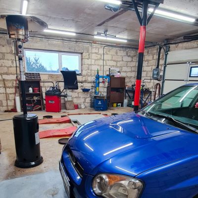 Garažas, kuriame montuoja padangas, stovi automobilis subaru, matosi keltuvas, montavimo ir balansavimo staklės